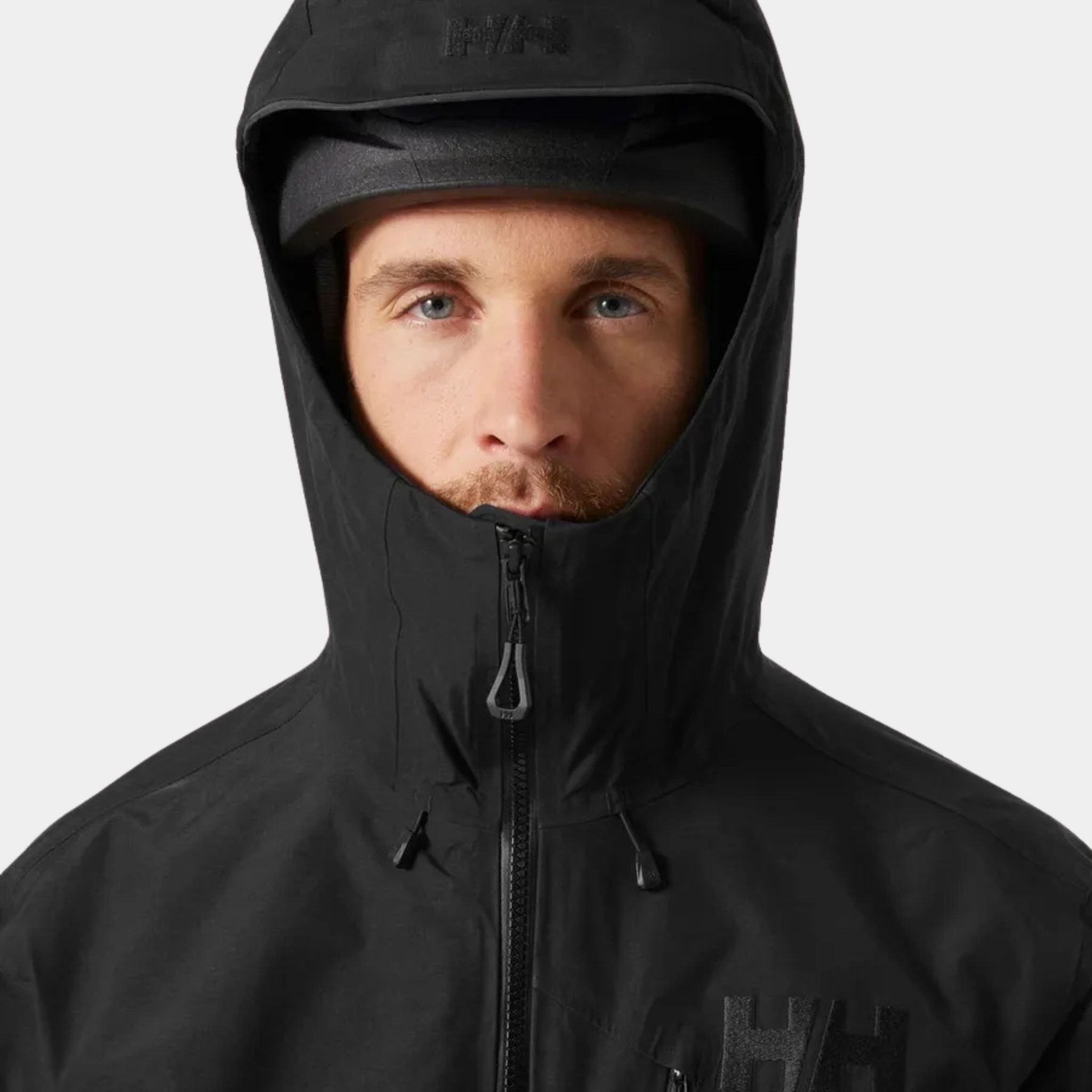 Male Model wearing a helmet under the Helly Hansen Odin 9 Worlds 3.0 Hard Shell Jacket in Black closeup