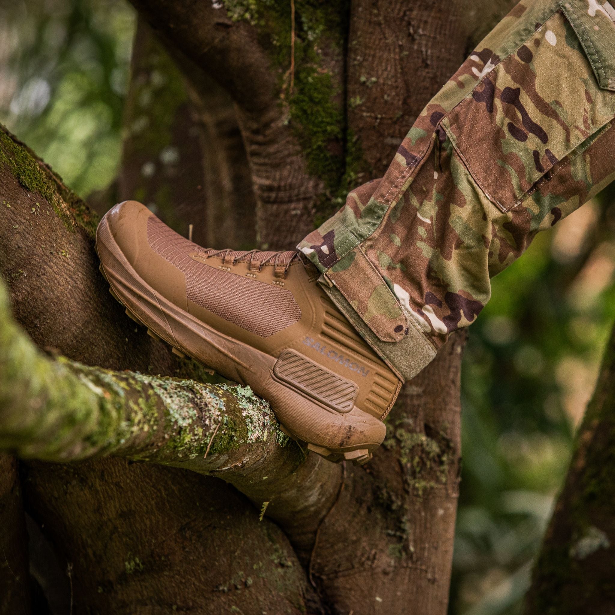 Someone climbing a tree wearing camouflage pants and the Salomon FORCES Genesis GTX in Coyote from S Elite